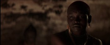 Movie still from “The Four Feathers” (2002), directed by Shekhar Kapur – A person with a necklace and earrings in a dark room; Close Up shot, Low angle