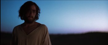 Movie still from “The Four Feathers” (2002), directed by Shekhar Kapur – A man with long hair is standing in front of a blue sky; Medium shot, Low angle