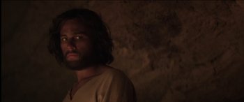 Movie still from “The Four Feathers” (2002), directed by Shekhar Kapur – A man with long hair and a beard is standing in a cave; Close Up shot, Low angle