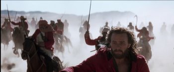 Movie still from “The Four Feathers” (2002), directed by Shekhar Kapur – A group of men in red jackets holding swords in a field; Medium shot, Low angle