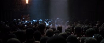 Movie still from “The Four Feathers” (2002), directed by Shekhar Kapur – A large group of people are gathered in a dark room; Extreme Wide shot, High angle