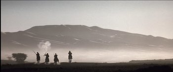 Movie still from “The Four Feathers” (2002), directed by Shekhar Kapur – Two people riding horses on a dirt field; Extreme Wide shot, Low angle