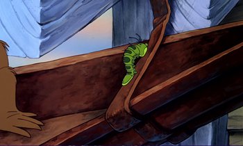 A green caterpillar sitting on top of a wooden bench