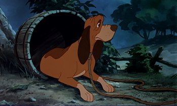 Movie still from “The Fox and the Hound” (1981), directed by Richard Rich – A brown and white dog sitting on top of a dirt field; Wide shot, Low angle