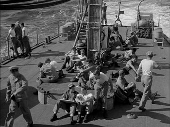 Movie still from “The Frogmen” (1951), directed by Lloyd Bacon – A black and white photo of people sitting on a boat; Wide shot, High angle