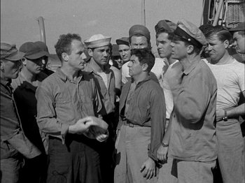 Movie still from “The Frogmen” (1951), directed by Lloyd Bacon – A black and white photo of a group of men standing together; Medium shot, High angle