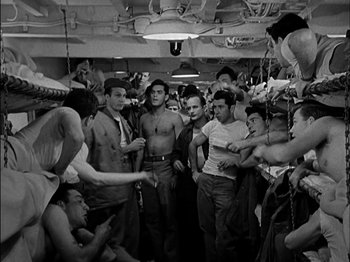 Movie still from “The Frogmen” (1951), directed by Lloyd Bacon – A group of men standing around in a room; Medium shot, High angle