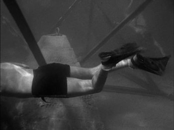 Movie still from “The Frogmen” (1951), directed by Lloyd Bacon – A man is hanging upside - down in the air; Wide shot, Overhead angle