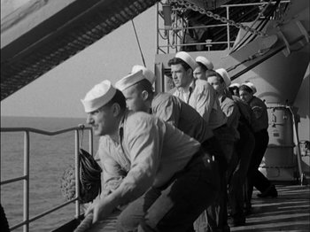 Movie still from “The Frogmen” (1951), directed by Lloyd Bacon – A black and white photo of a group of men on a boat; Medium shot, Low angle