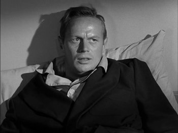 Movie still from “The Frogmen” (1951), directed by Lloyd Bacon – A man sitting in a bed wearing a suit and tie; Close Up shot, High angle