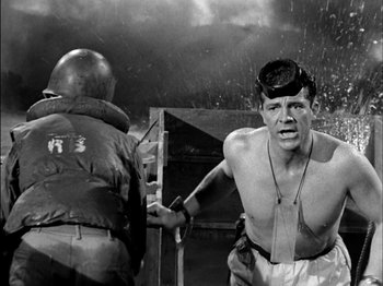 Movie still from “The Frogmen” (1951), directed by Lloyd Bacon – A man in a black and white photo with another man in a black and white photo; Medium shot, Low angle
