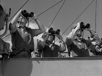 Movie still from “The Frogmen” (1951), directed by Lloyd Bacon – A group of men standing on top of a boat looking through binoculars; Medium shot, Low angle