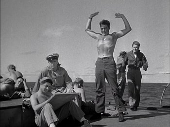 Movie still from “The Frogmen” (1951), directed by Lloyd Bacon – A group of men standing on top of a boat; Medium shot, Low angle