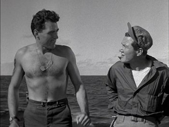 Movie still from “The Frogmen” (1951), directed by Lloyd Bacon – Two men holding hands while standing in the ocean; Medium shot, Low angle
