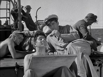 Movie still from “The Frogmen” (1951), directed by Lloyd Bacon – A black and white photo of a group of men sitting on a boat; Medium shot, High angle