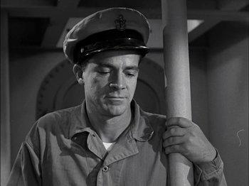 Movie still from “The Frogmen” (1951), directed by Lloyd Bacon – A man wearing a hat is holding a flag pole; Close Up shot, Low angle