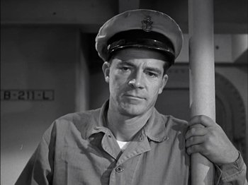 Movie still from “The Frogmen” (1951), directed by Lloyd Bacon – Black and white photograph of a man wearing a hat; Close Up shot, Low angle
