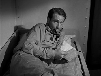 Movie still from “The Frogmen” (1951), directed by Lloyd Bacon – A black and white photo of a man sitting in a bed; Close Up shot, High angle
