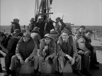 Movie still from “The Frogmen” (1951), directed by Lloyd Bacon – A black and white photo of a group of men sitting on a boat; Wide shot, High angle