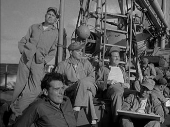 Movie still from “The Frogmen” (1951), directed by Lloyd Bacon – A black and white photo of a group of men sitting on top of a boat; Wide shot, High angle