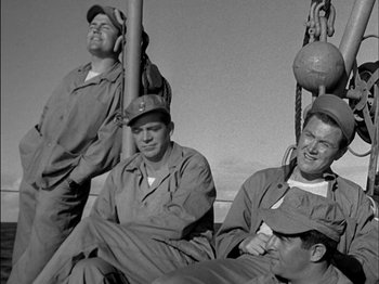 Movie still from “The Frogmen” (1951), directed by Lloyd Bacon – A group of men sitting next to each other on top of a boat; Medium shot, Low angle