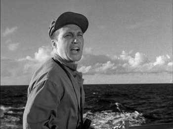 Movie still from “The Frogmen” (1951), directed by Lloyd Bacon – A man standing in front of a body of water; Close Up shot, Low angle