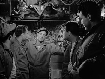 Movie still from “The Frogmen” (1951), directed by Lloyd Bacon – A group of men standing next to each other in a room; Medium shot, High angle
