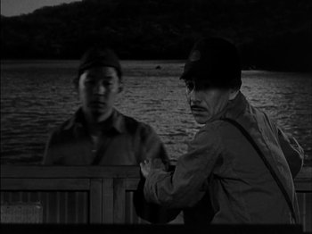 Movie still from “The Frogmen” (1951), directed by Lloyd Bacon – Two men sitting on a bench near a body of water; Medium shot, Over the shoulder angle