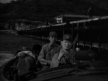 Movie still from “The Frogmen” (1951), directed by Lloyd Bacon – A black and white photo of two men on a boat; Medium shot, Over the shoulder angle