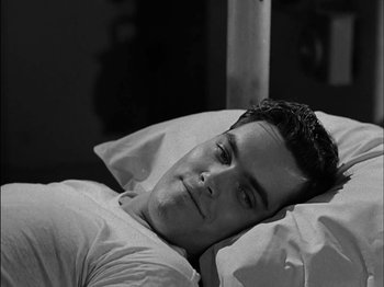 Movie still from “The Frogmen” (1951), directed by Lloyd Bacon – A man laying in a bed with his head on a pillow; Close Up shot, High angle