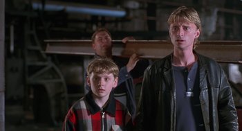 Movie still from “The Full Monty” (1997), directed by Peter Cattaneo – Two men and a young boy standing next to each other in a warehouse; Medium shot, Low angle