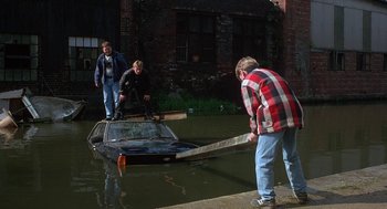 Movie still from “The Full Monty” (1997), directed by Peter Cattaneo – Three men standing on a boat in a body of water; Wide shot, High angle