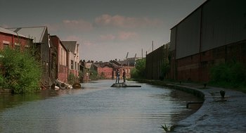 Movie still from “The Full Monty” (1997), directed by Peter Cattaneo – A couple of people standing on top of a boat in the water; Extreme Wide shot, High angle