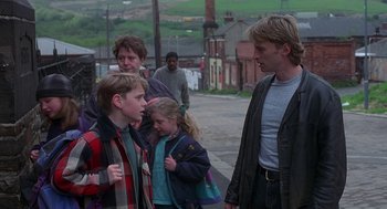 Movie still from “The Full Monty” (1997), directed by Peter Cattaneo – A group of people standing on the side of a road; Medium shot, Over the shoulder angle