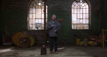 Movie still from “The Full Monty” (1997), directed by Peter Cattaneo – A man standing next to a pole in a room; Wide shot, Low angle