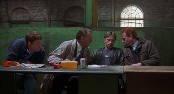 Movie still from “The Full Monty” (1997), directed by Peter Cattaneo – A group of people sitting around a table; Medium shot, Over the shoulder angle