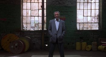 Movie still from “The Full Monty” (1997), directed by Peter Cattaneo – A man in a suit standing in front of a window; Wide shot, Low angle