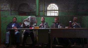 Movie still from “The Full Monty” (1997), directed by Peter Cattaneo – Two men are sitting at a table reading newspapers; Wide shot, Low angle