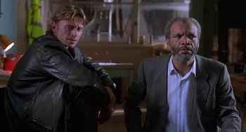 Movie still from “The Full Monty” (1997), directed by Peter Cattaneo – Two men standing next to each other in a room; Medium shot, Low angle