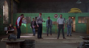 Movie still from “The Full Monty” (1997), directed by Peter Cattaneo – A group of people standing in front of a green wall; Wide shot, Low angle