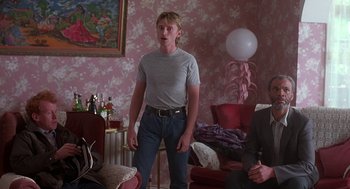 Movie still from “The Full Monty” (1997), directed by Peter Cattaneo – A man standing in a living room next to another man; Medium shot, Over the shoulder angle