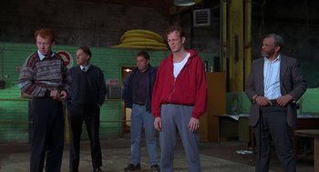 Movie still from “The Full Monty” (1997), directed by Peter Cattaneo – A group of men standing next to each other in a room; Medium shot, Low angle