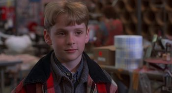 Movie still from “The Full Monty” (1997), directed by Peter Cattaneo – A young boy in a plaid jacket in a warehouse; Close Up shot, Over the shoulder angle
