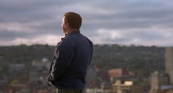 Movie still from “The Full Monty” (1997), directed by Peter Cattaneo – A man standing on top of a hill looking out at a city; Medium shot, High angle