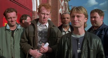 Movie still from “The Full Monty” (1997), directed by Peter Cattaneo – A group of men standing next to each other on a street; Medium shot, Low angle