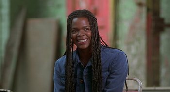 Movie still from “The Full Monty” (1997), directed by Peter Cattaneo – A person with long braids smiles for the camera; Close Up shot, Low angle