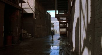 Movie still from “The Full Monty” (1997), directed by Peter Cattaneo – A person walking down a street in an alley way; Extreme Wide shot, High angle