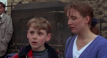 Movie still from “The Full Monty” (1997), directed by Peter Cattaneo – A woman and a boy standing next to each other; Close Up shot, Over the shoulder angle