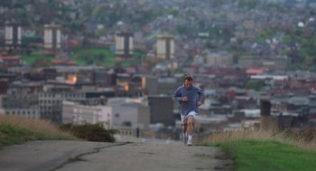 Movie still from “The Full Monty” (1997), directed by Peter Cattaneo – A man is running on a hill with a city in the background; Extreme Wide shot, High angle