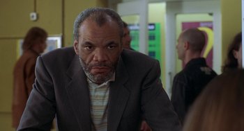 Movie still from “The Full Monty” (1997), directed by Peter Cattaneo – An older man in a suit is looking at the camera; Close Up shot, Low angle